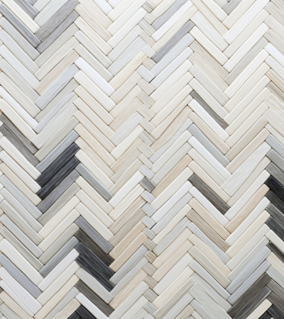 Herringbone Wall Tile: Gray And Greyhyacinth Wood With Textured Backgrounds herringbone tile in grey and black creates a visually striking pattern on a wall. the colorful textures, including light indigo and beige, add depth and interest against a white background. sculptural paper constructions and natural fibers enhance the overall design, while repetition and accumulation create a sense of harmony. the light silver and light brown tones add a touch of elegance to the space. ai