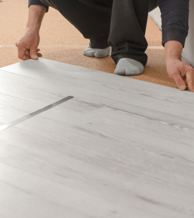 Unrecognizable man laying laminate flooring. Repair in the apartment. Professional laying of a floor covering – a laminate. Laminate installation process Unrecognizable man laying laminate flooring. Repair in the apartment. Professional laying of a floor covering - a laminate. Laminate installation process